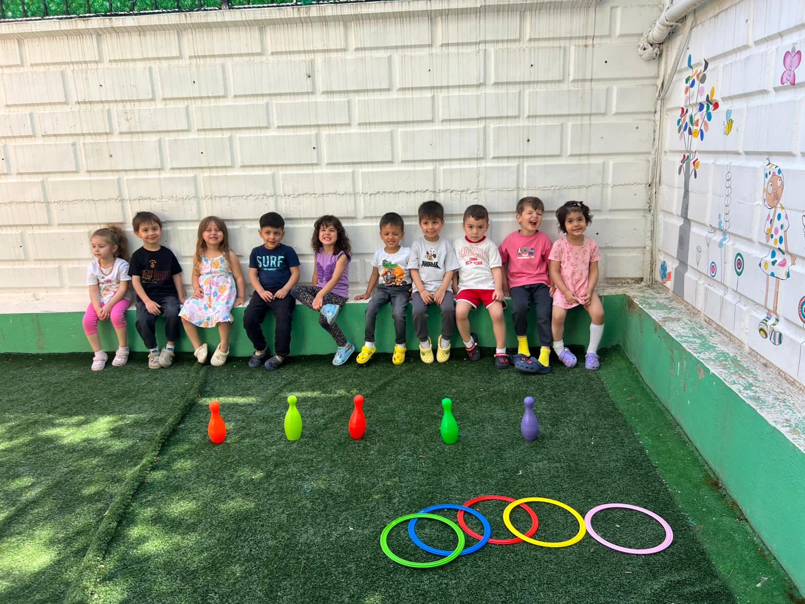 Özgün Çocuklar bahçesinde renkli koni ve halkalarla parkur etkinliği yapan çocuklar
